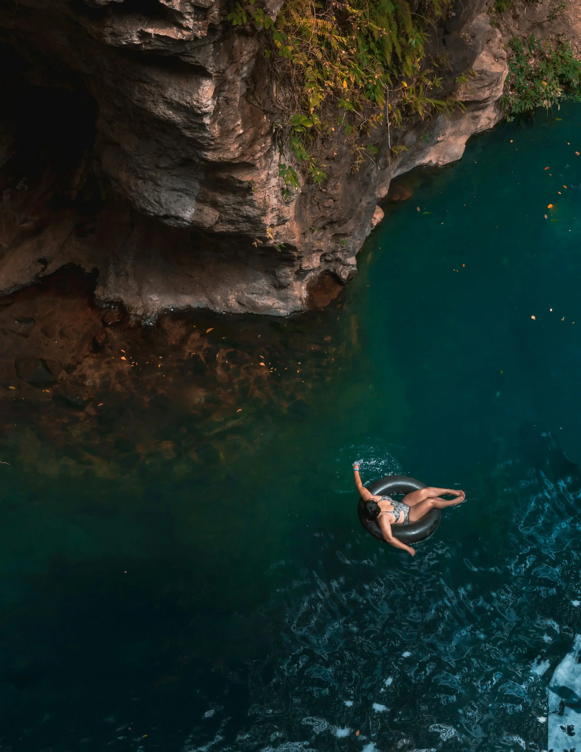 Woman floating on a rubber floaty in river with blue water.